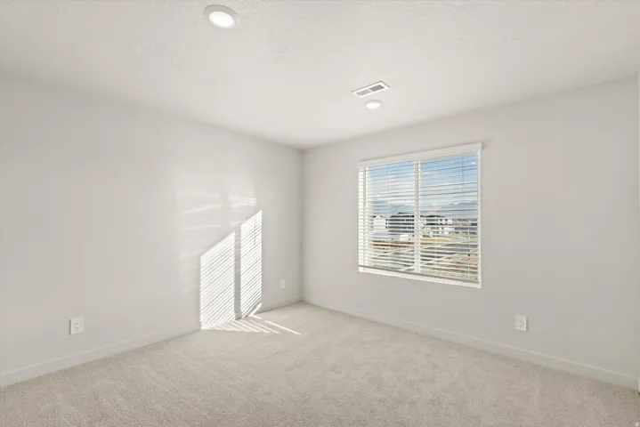 Neutral-toned interior featuring recessed lighting, a window with horizontal blinds, and light-colored carpet flooring