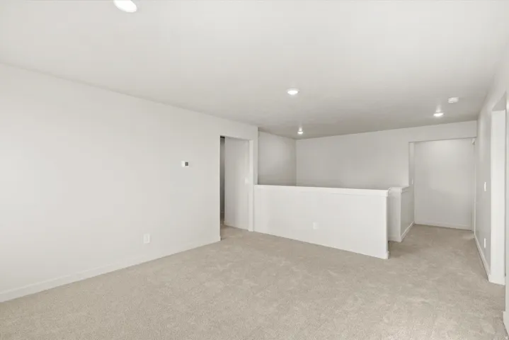 Spacious secondary living area featuring plush carpeting and a neutral color palette