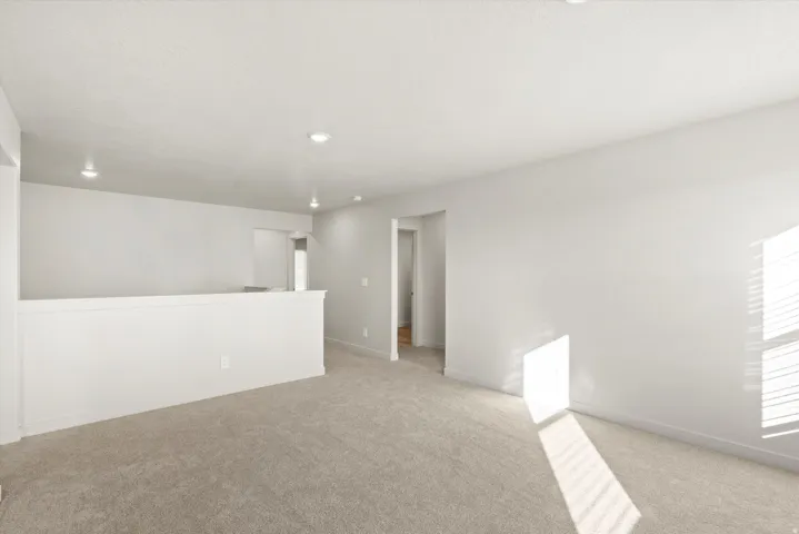 Upper-level landing featuring neutral carpet flooring, recessed lighting, and white wall finishes