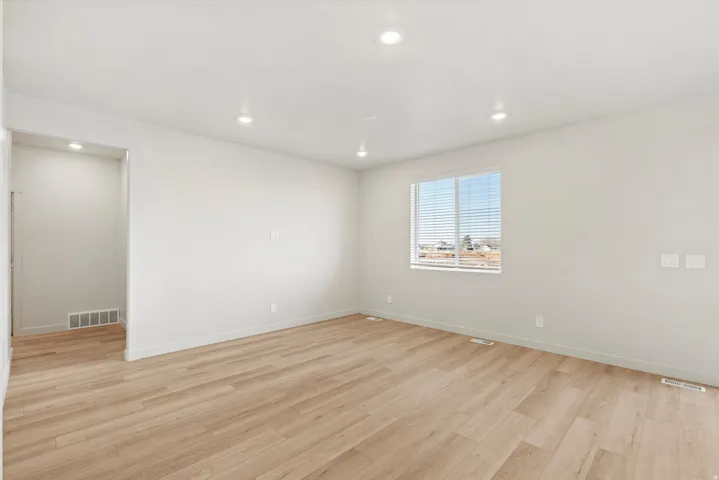 Spacious room featuring wood-finish flooring, recessed lighting, neutral wall tones, white trim, and a window with horizontal blinds