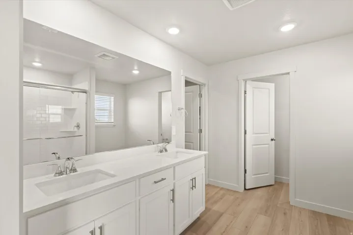 Bathroom featuring a dual vanity with undermount sinks, white cabinetry, and a full-width mirror