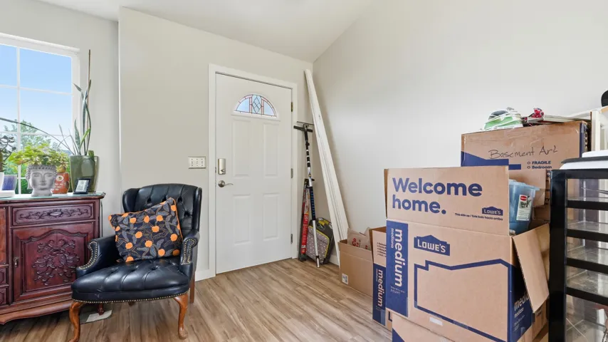 Entryway featuring LVP, a white paneled door with an arched decorative glass insert, and neutral wall paint