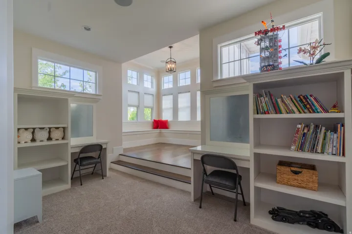 Multi-level room with built-in desks, shelving, and a raised area featuring wood-finish flooring