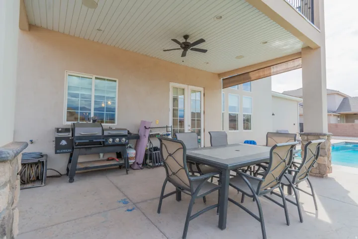 Covered patio area featuring a ceiling fan, dual-pane windows, and stucco exterior
