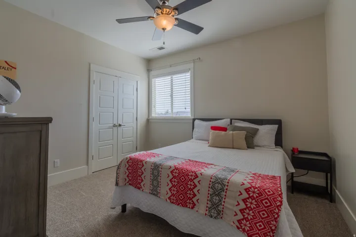 Carpeted room featuring a ceiling fan with integrated lighting, a window with horizontal blinds, and a built-in closet with double panel doors