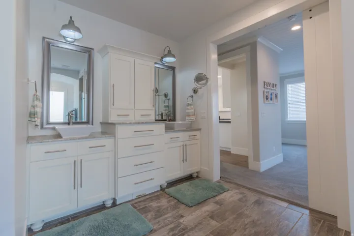 Bathroom featuring dual vanities with vessel sinks, granite countertops, and white cabinetry