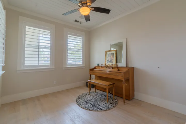 Room featuring two windows with white plantation shutters, wood-finish flooring, and a white plank ceiling with a ceiling fan