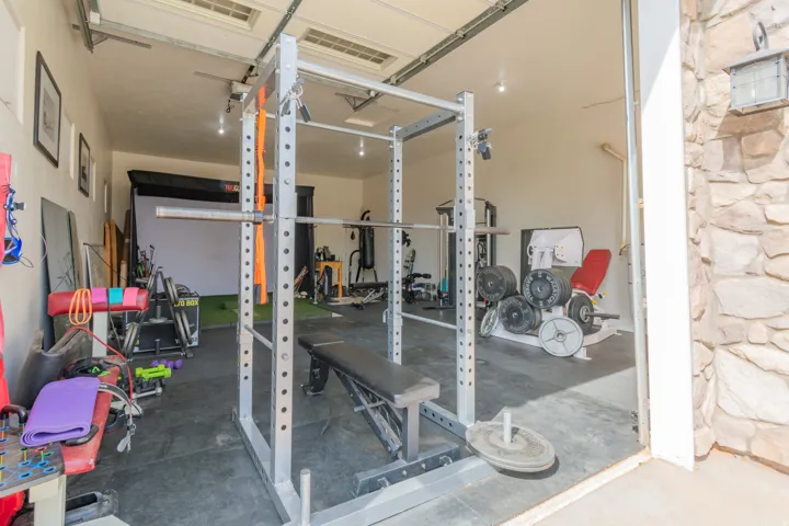 Dedicated garage space featuring a roll-up door, exposed ceiling tracks, recessed lighting, and a stone facade exterior element