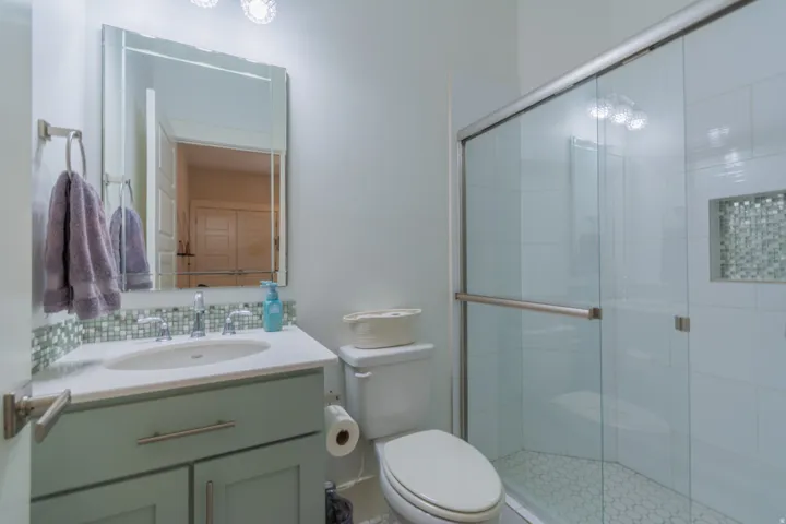 Bathroom featuring a glass-enclosed shower with a mosaic tile niche, white subway tile surround, and hexagonal floor tile