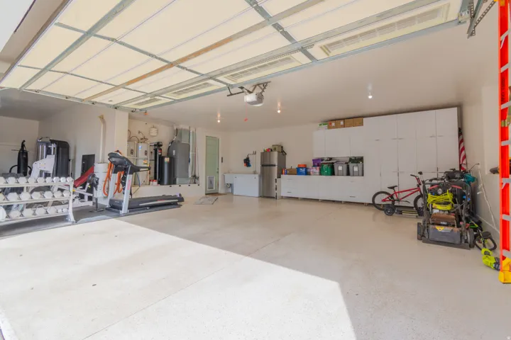 Spacious garage featuring a light-colored epoxy floor coating, recessed lighting, and extensive built-in white cabinetry for organized storage