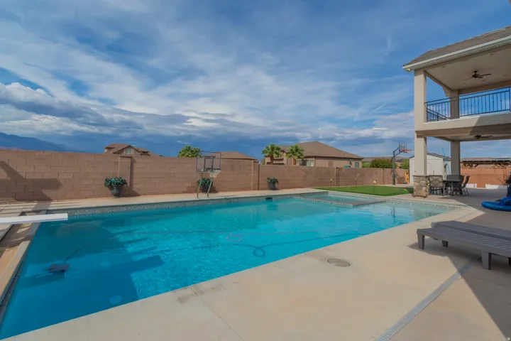 Expansive backyard featuring a large swimming pool with a diving board, a separate hot tub, and a compact putting green