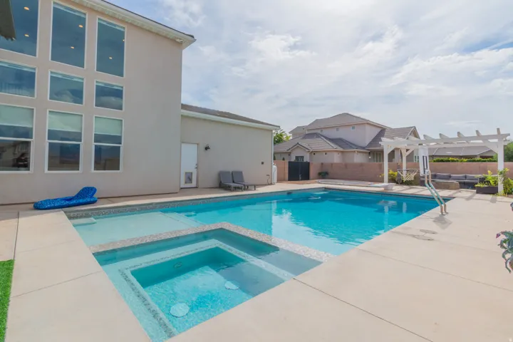 Outdoor swimming pool featuring an integrated spa and sun shelf
