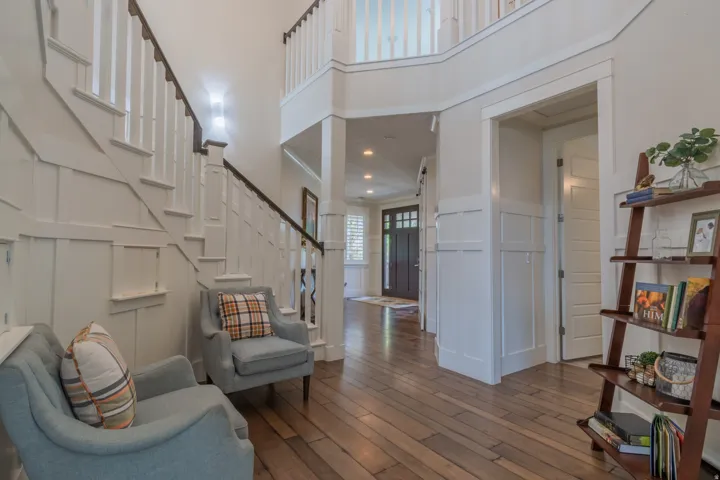 Two-story entry foyer featuring wood-finish flooring, white wainscoting, and a prominent staircase with dark wood handrails