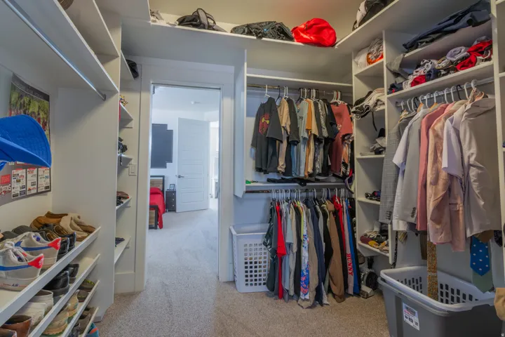 Spacious walk-in closet featuring extensive built-in shelving, multiple hanging rods, and dedicated shoe storage