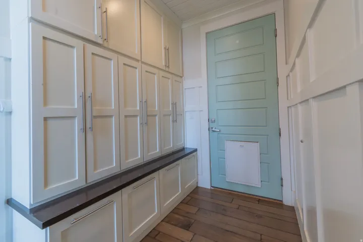 Entryway featuring extensive built-in cabinetry with shaker-style doors and brushed nickel hardware, a dark wood-finish countertop, and wood-finish flooring