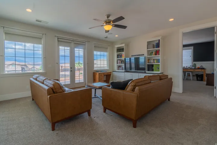 Spacious living area featuring neutral carpet flooring and a ceiling fan with integrated lighting
