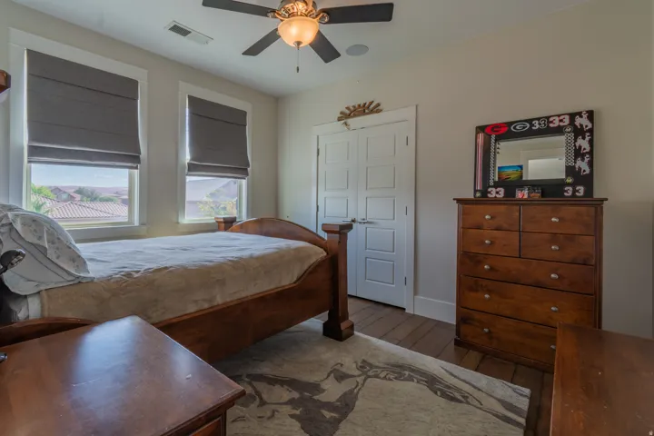 Bedroom with two windows featuring Roman shades and a ceiling fan