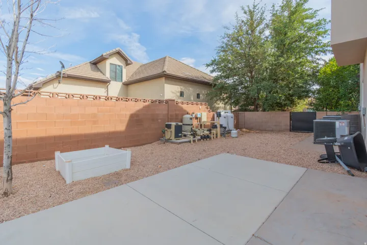 Hardscaped outdoor area featuring a concrete patio, pea gravel landscaping, and a privacy block wall