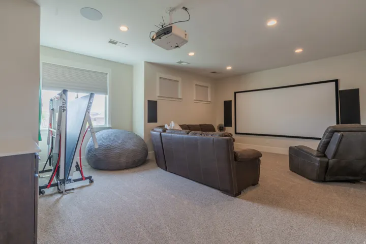 Dedicated media room featuring a large projection screen, two built-in speakers, and a ceiling-mounted projector