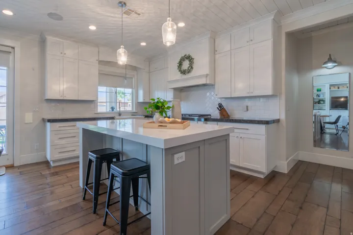 Kitchen featuring a large central island with seating, white shaker-style cabinetry, a tile backsplash, wood-finish flooring, and a decorative shiplap ceiling