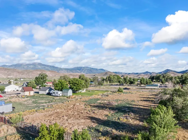 Expansive rural landscape featuring distant mountains and scattered residential structures
