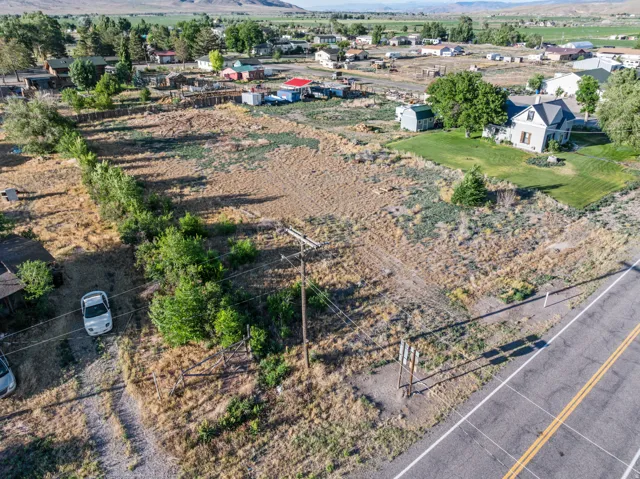 Expansive land parcel featuring existing infrastructure, mature trees, and a road frontage