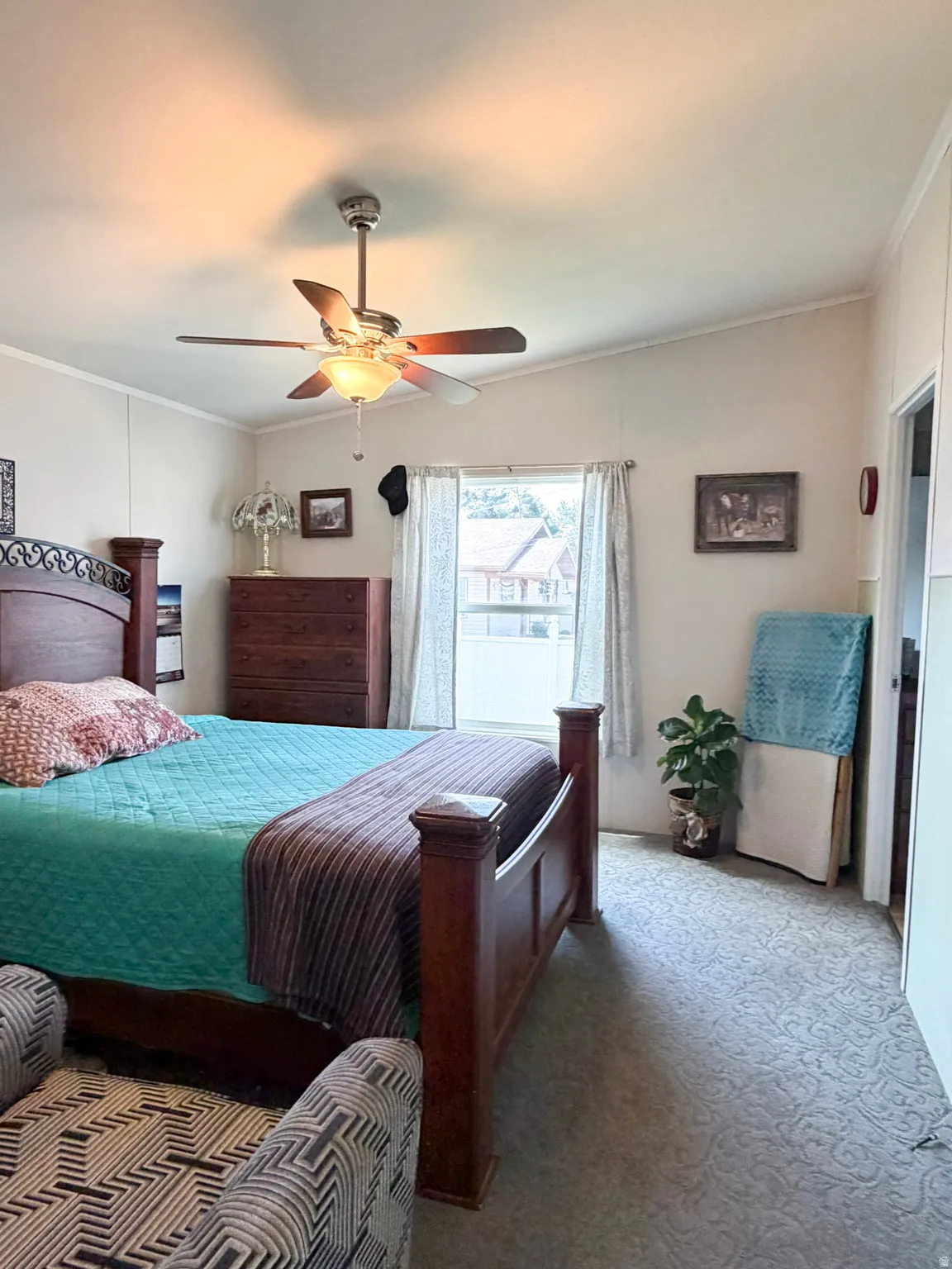 Spacious bedroom featuring vaulted ceilings, a ceiling fan with integrated lighting, patterned carpeting, and a window with natural light