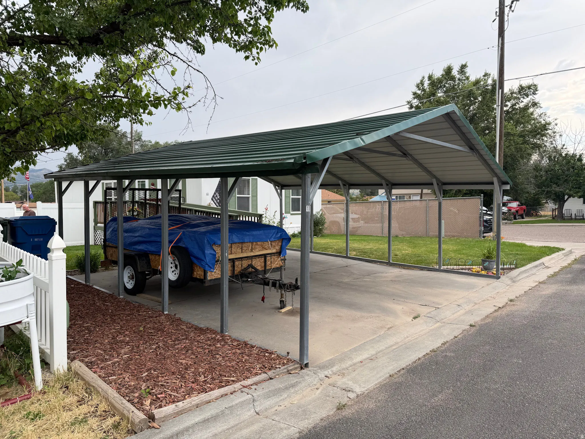 Concrete driveway with a green metal carport structure