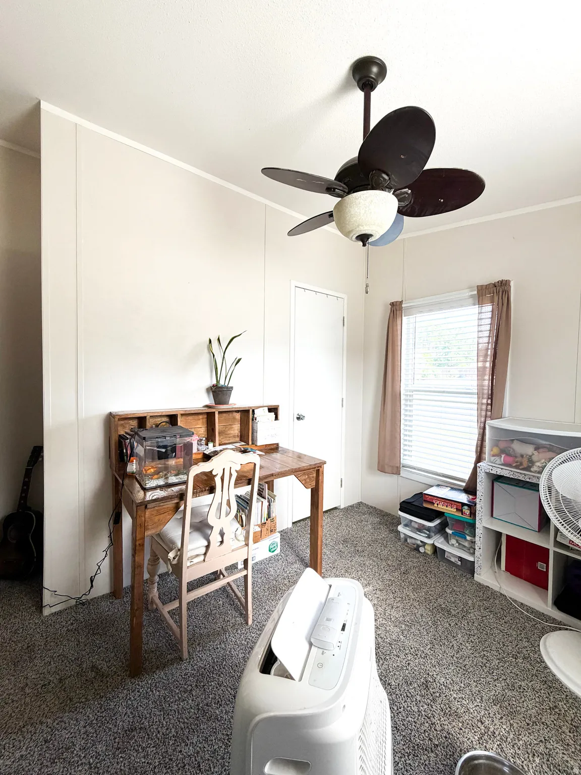 Carpeted room featuring a ceiling fan with integrated lighting, paneled walls, and a window with blinds