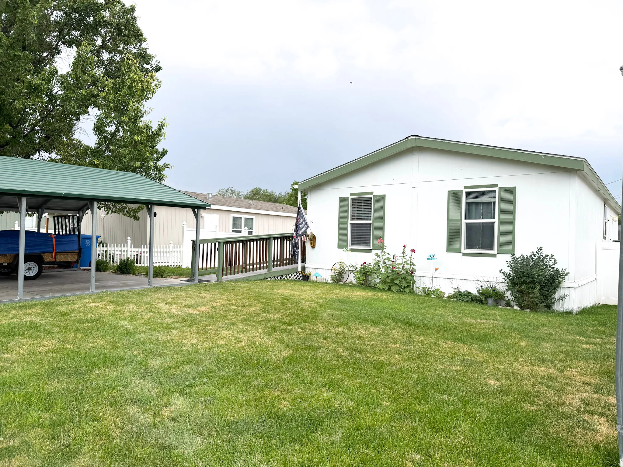 White siding residence featuring green trim and shutters, a covered carport, and a ramp entrance