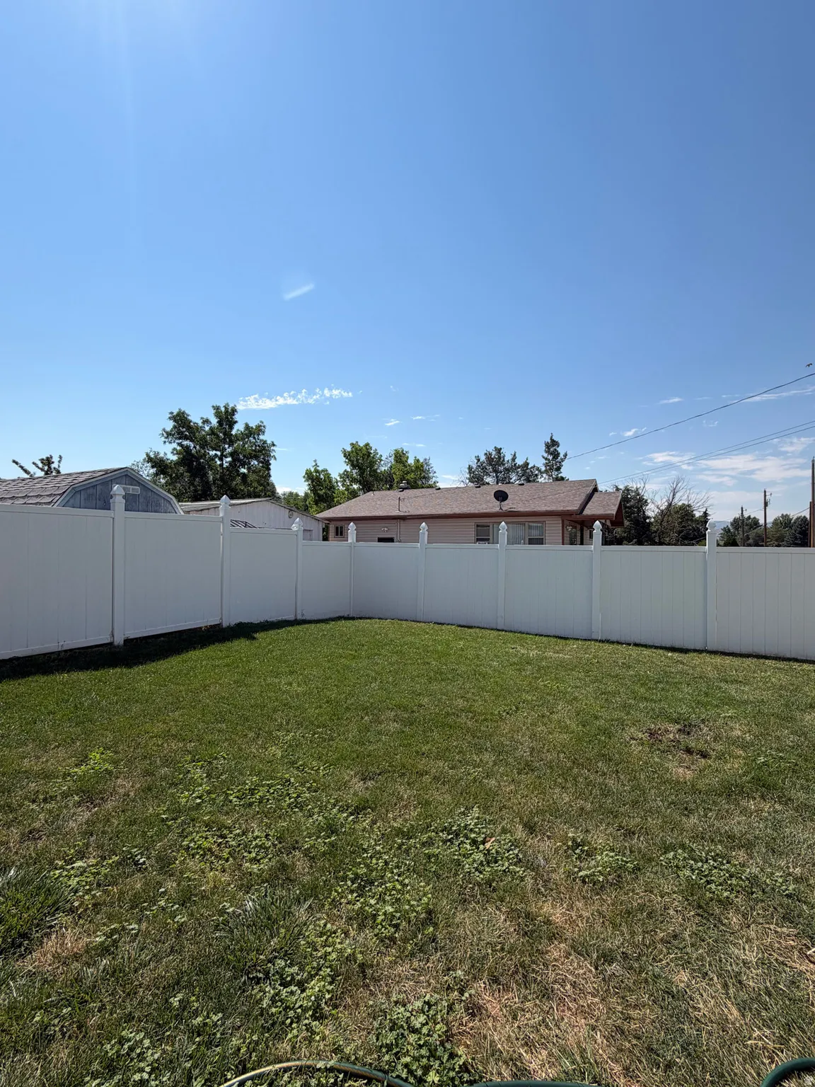 Fenced backyard featuring a lawn area and white privacy fencing