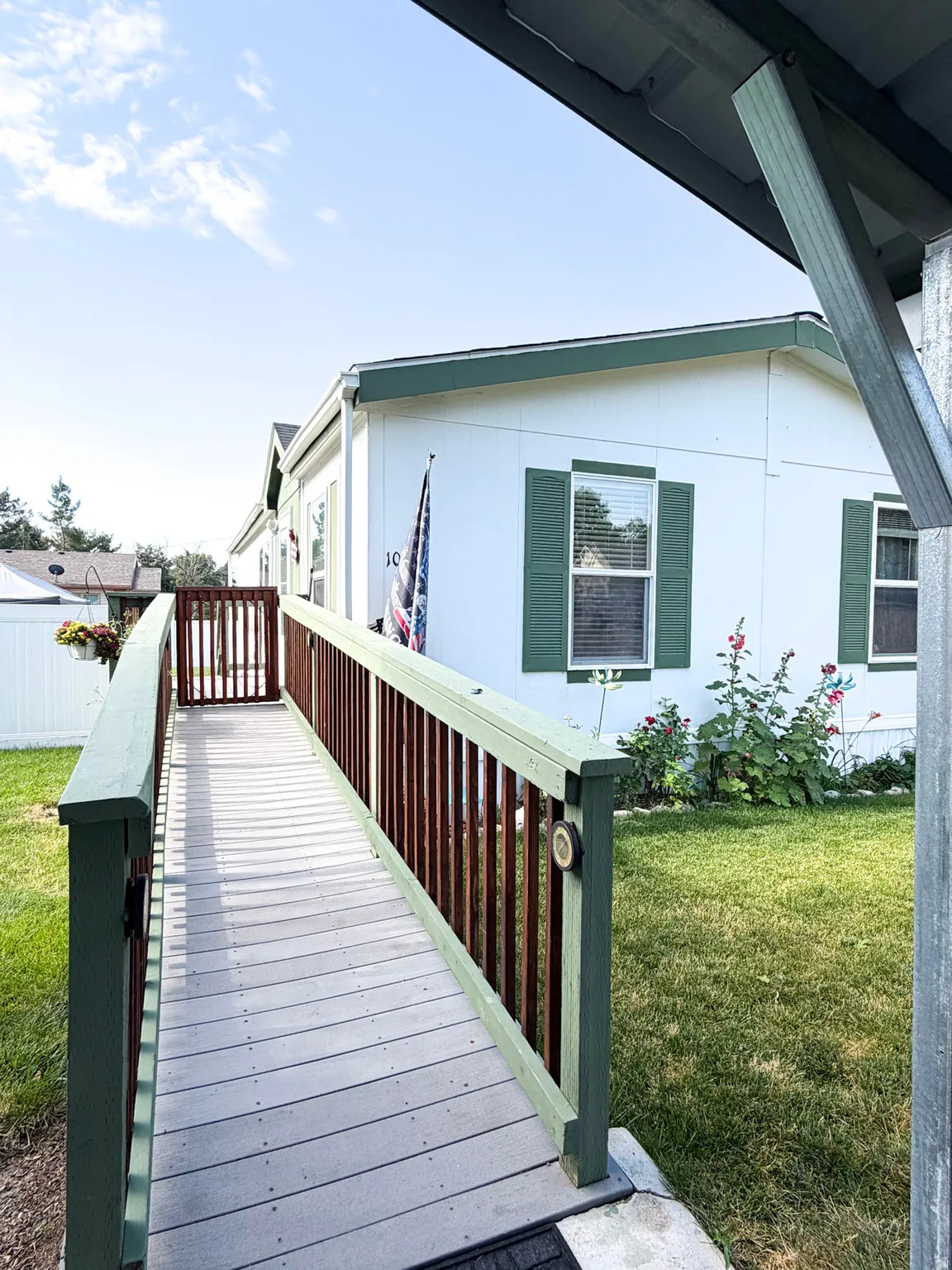 Property exterior featuring a white facade with green shutters, a ramp entrance, and an adjacent grassy area