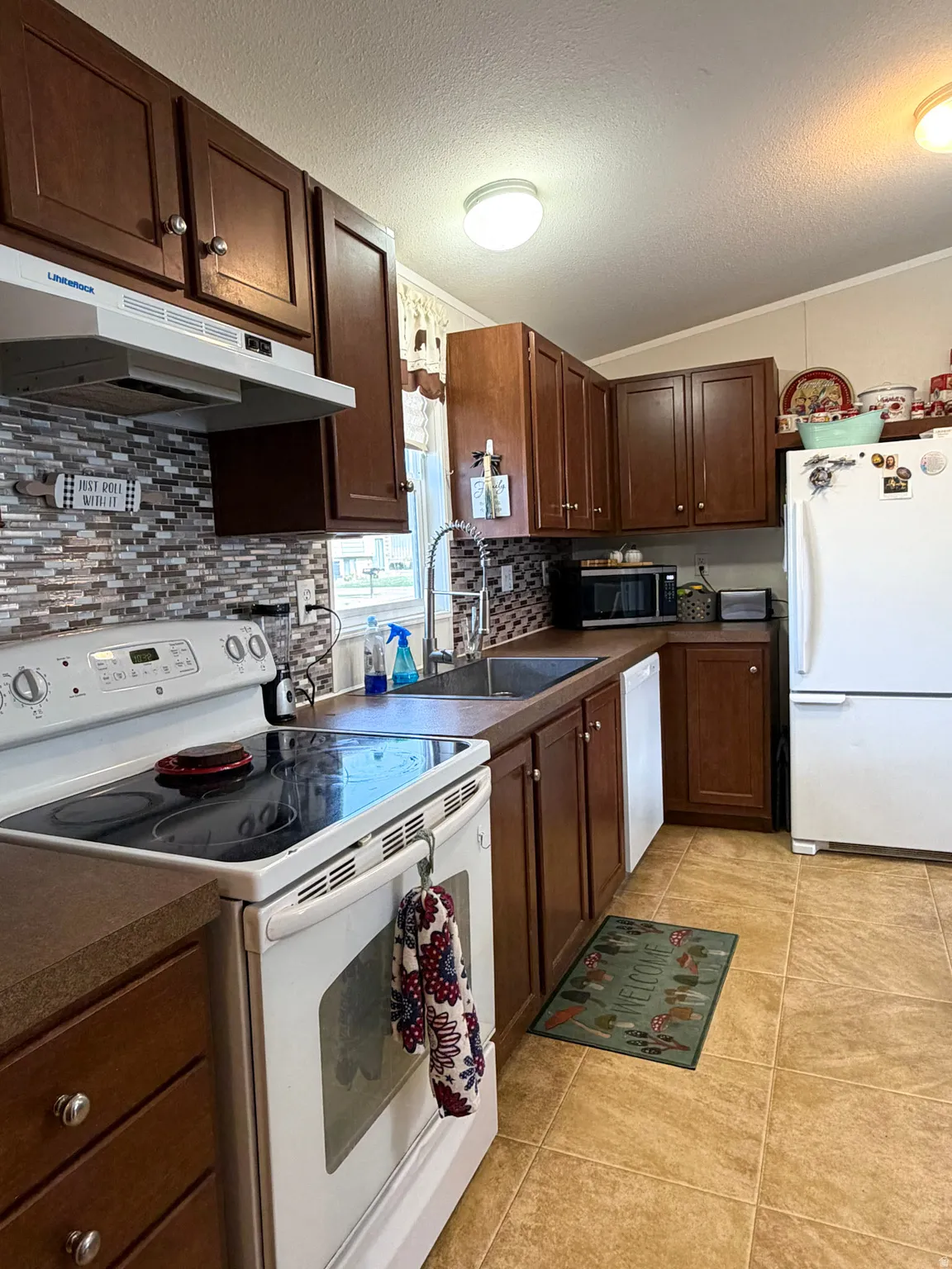 Kitchen featuring wood cabinetry, brown countertops, and a mosaic tile backsplash
