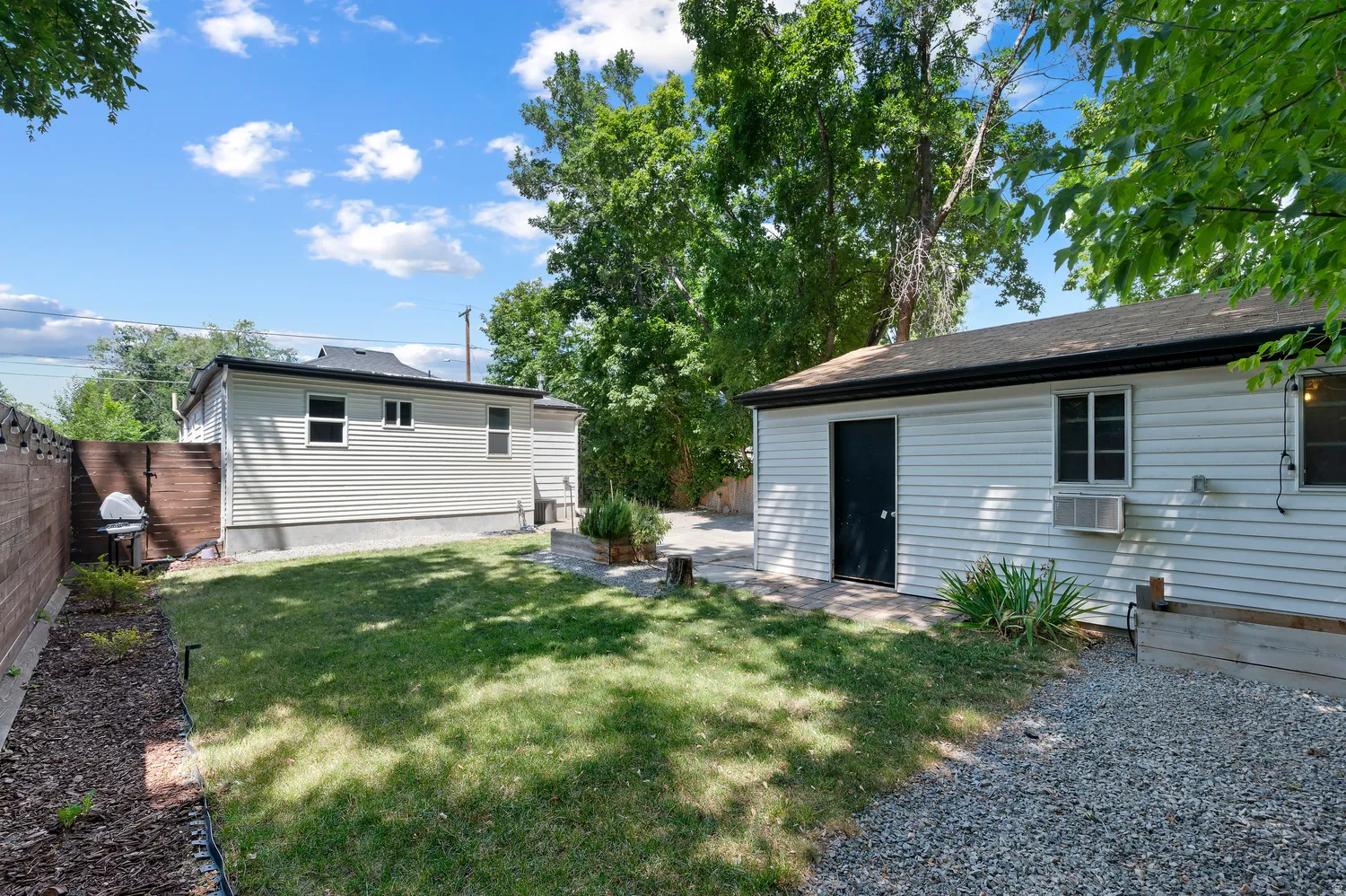 Expansive backyard featuring a manicured lawn, gravel area, and a privacy fence