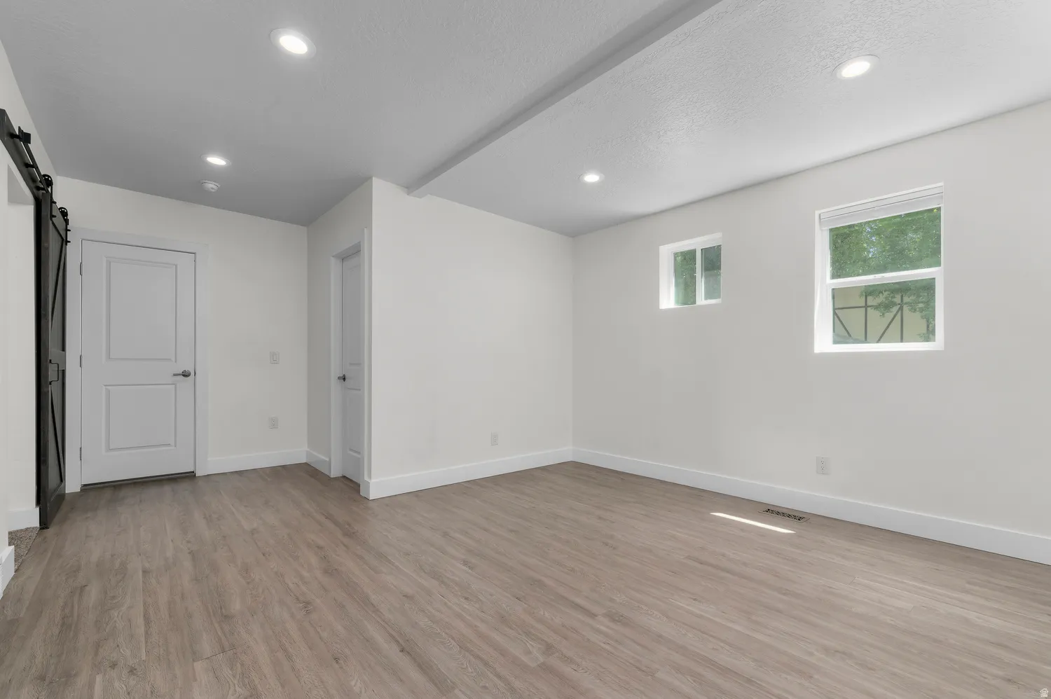 Bright interior space featuring wood-finish flooring, recessed lighting, and a modern barn door