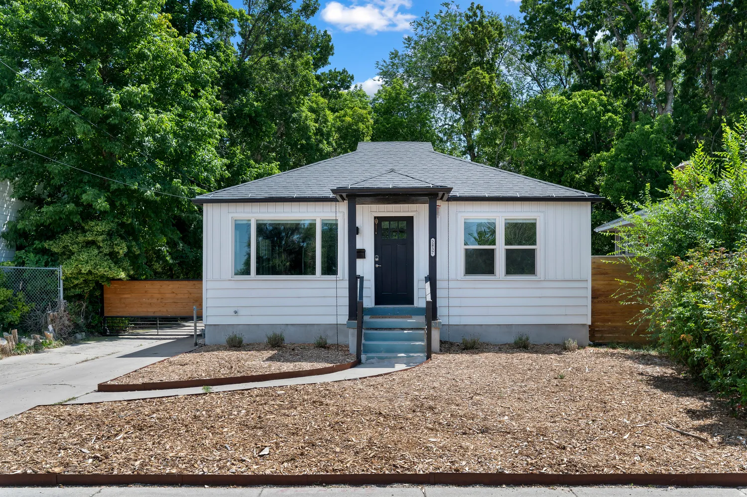 White siding exterior with a dark front door, covered entry, and dark trim