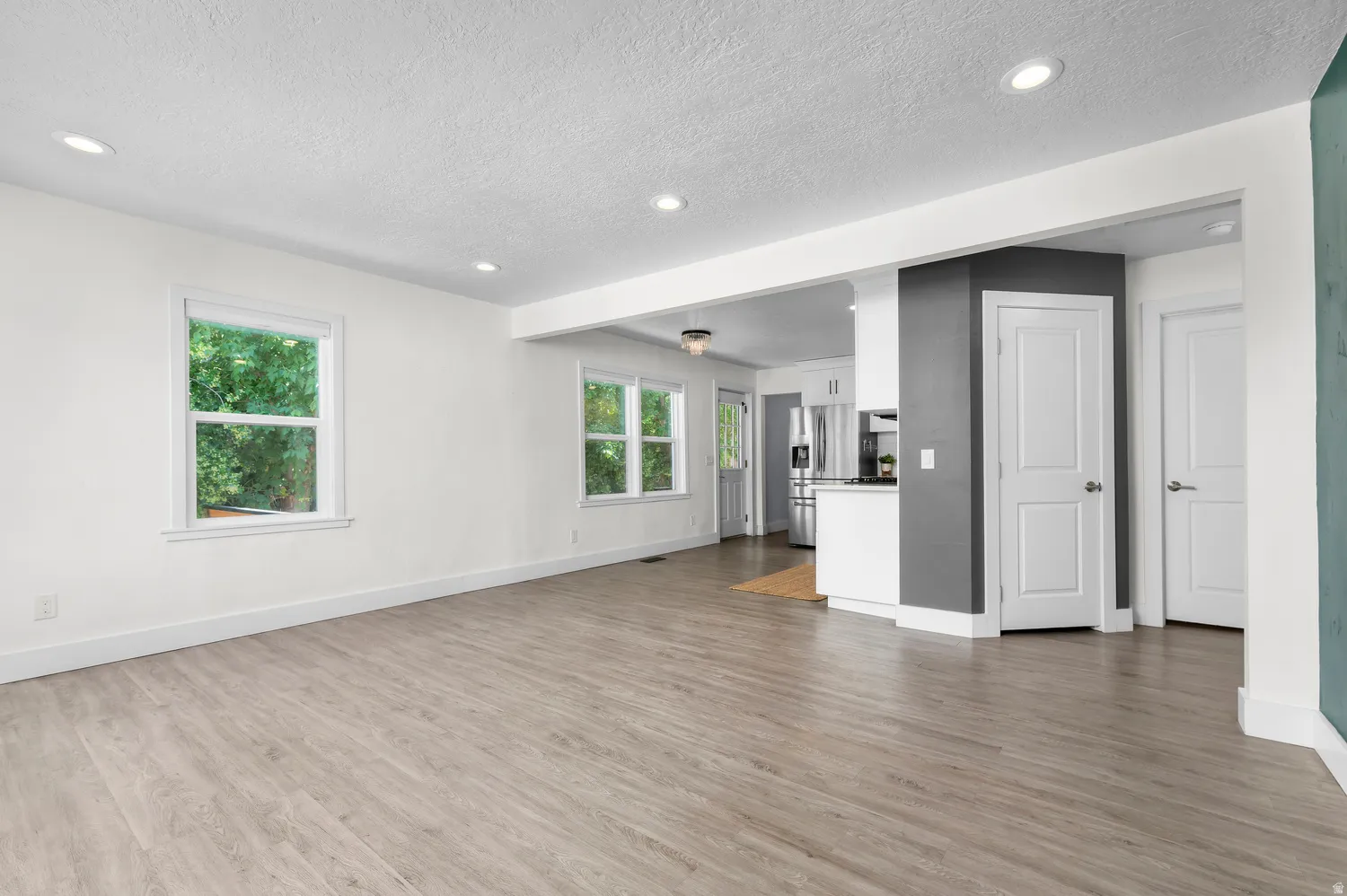Expansive open-concept room featuring light wood-finish flooring, recessed lighting, and crisp white walls