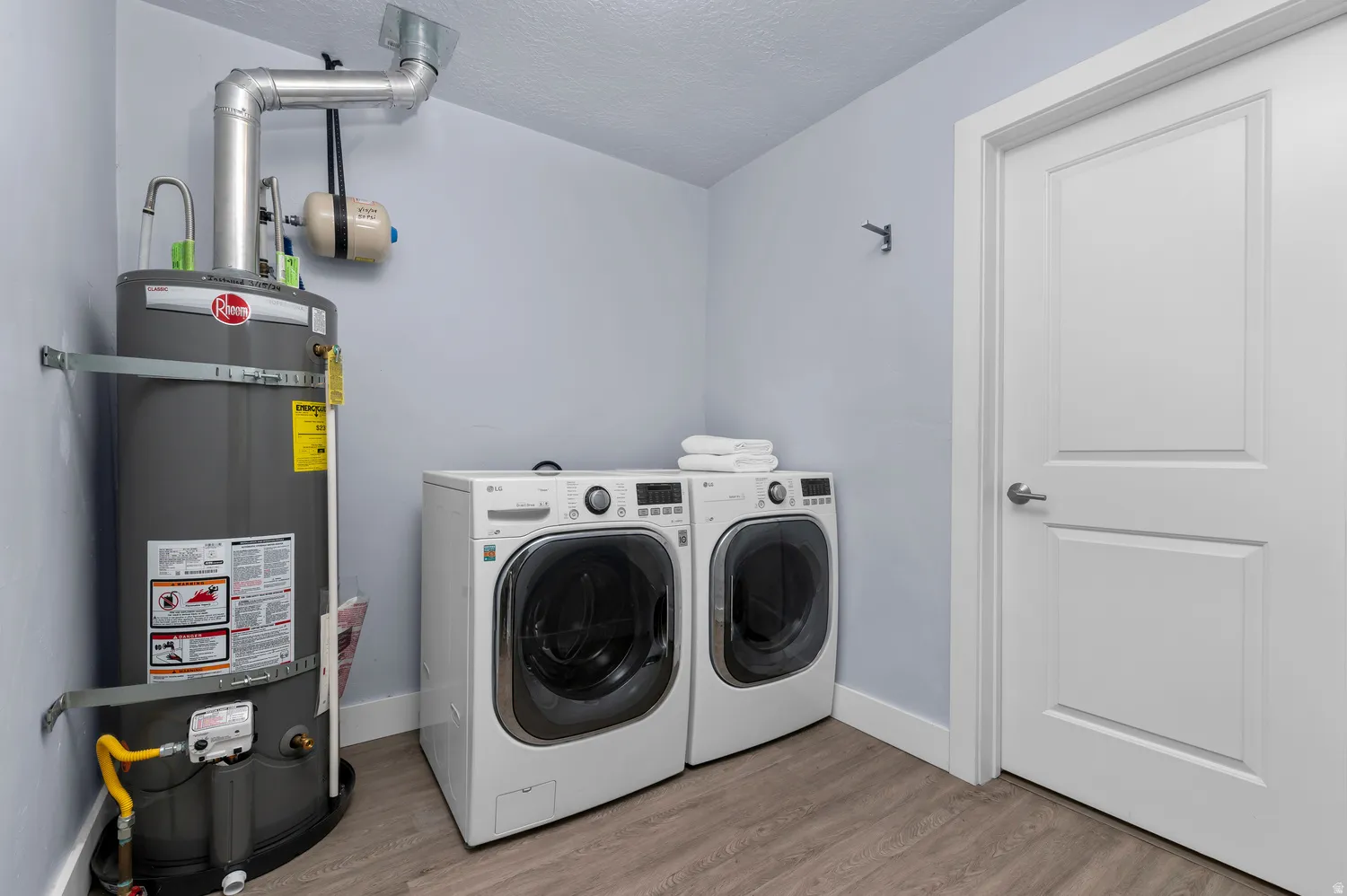 Utility space featuring a water heater, washer, and dryer units
