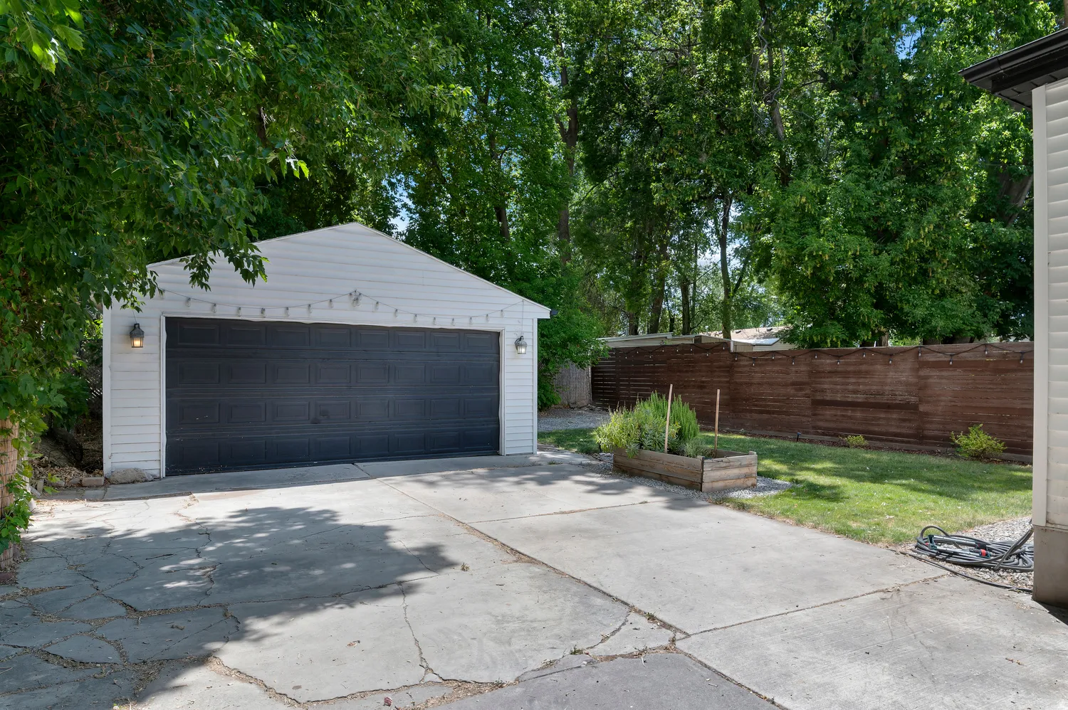 Detached two-car garage with white siding and a dark garage door