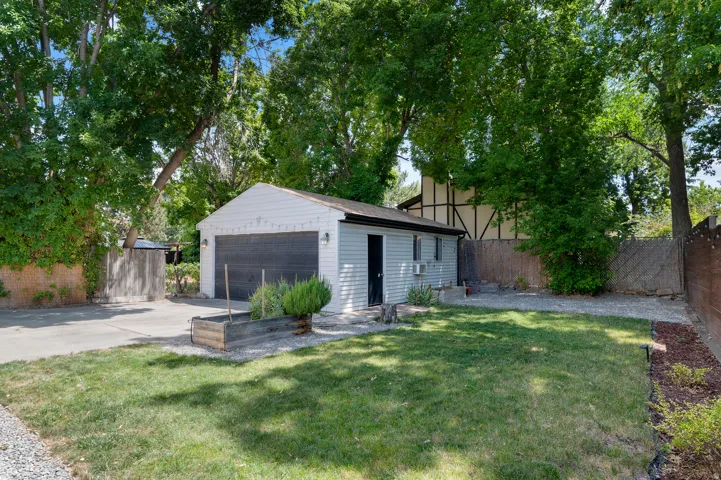 Detached garage with light-colored siding, dark garage door, and side entry door