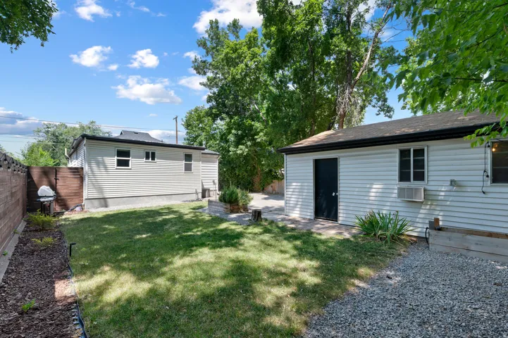 Expansive backyard featuring a manicured lawn, gravel area, and a privacy fence