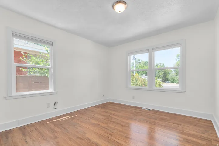 Bright room featuring wood-finish flooring, white painted walls, and white trim