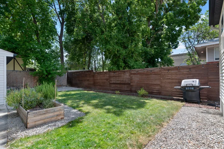 Private backyard featuring a horizontal plank fence, a raised garden bed, and a gravel perimeter