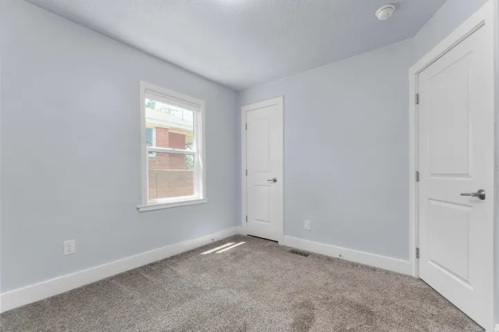 Room featuring light blue walls, white trim, and gray carpeting