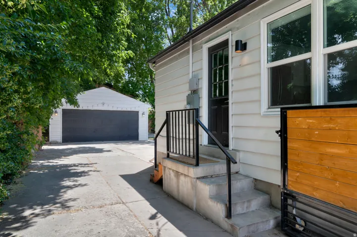 Detached two-car garage with a dark gray overhead door and exterior lighting