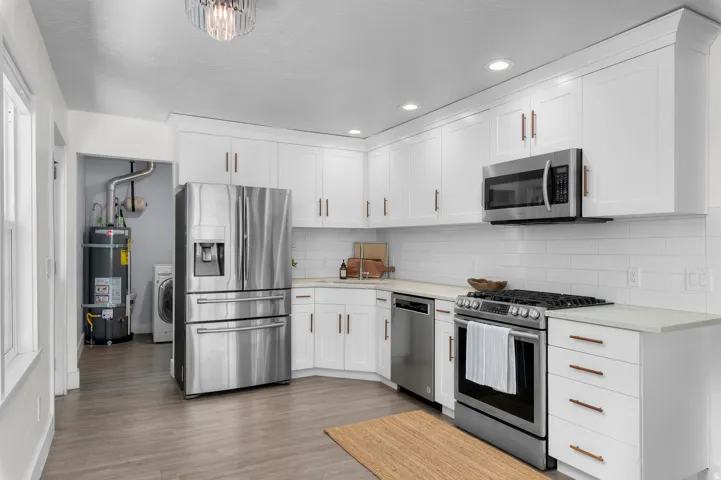 Modern kitchen featuring white shaker cabinetry, stainless steel appliances, light countertops, and subway tile backsplash