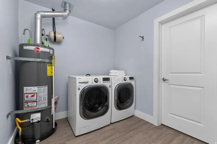 Utility space featuring a water heater, washer, and dryer units
