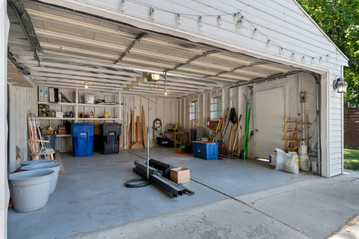 Attached two-car garage featuring a concrete floor, built-in shelving, two windows, and a side-entry door