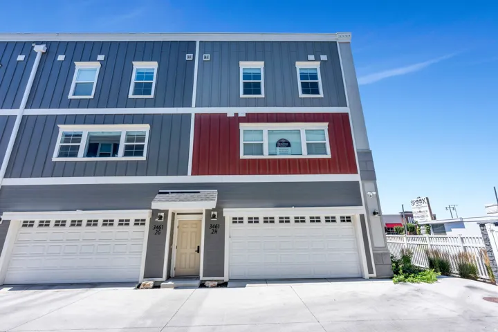 Multi-story townhouse exterior with vertical panel siding in blue-gray and a red-accented section