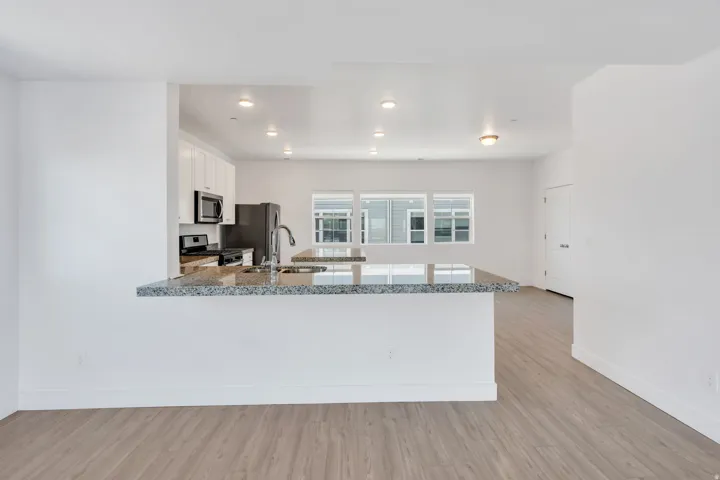 Kitchen featuring granite countertops, stainless steel appliances, recessed lighting, white cabinetry, and wood-finish flooring